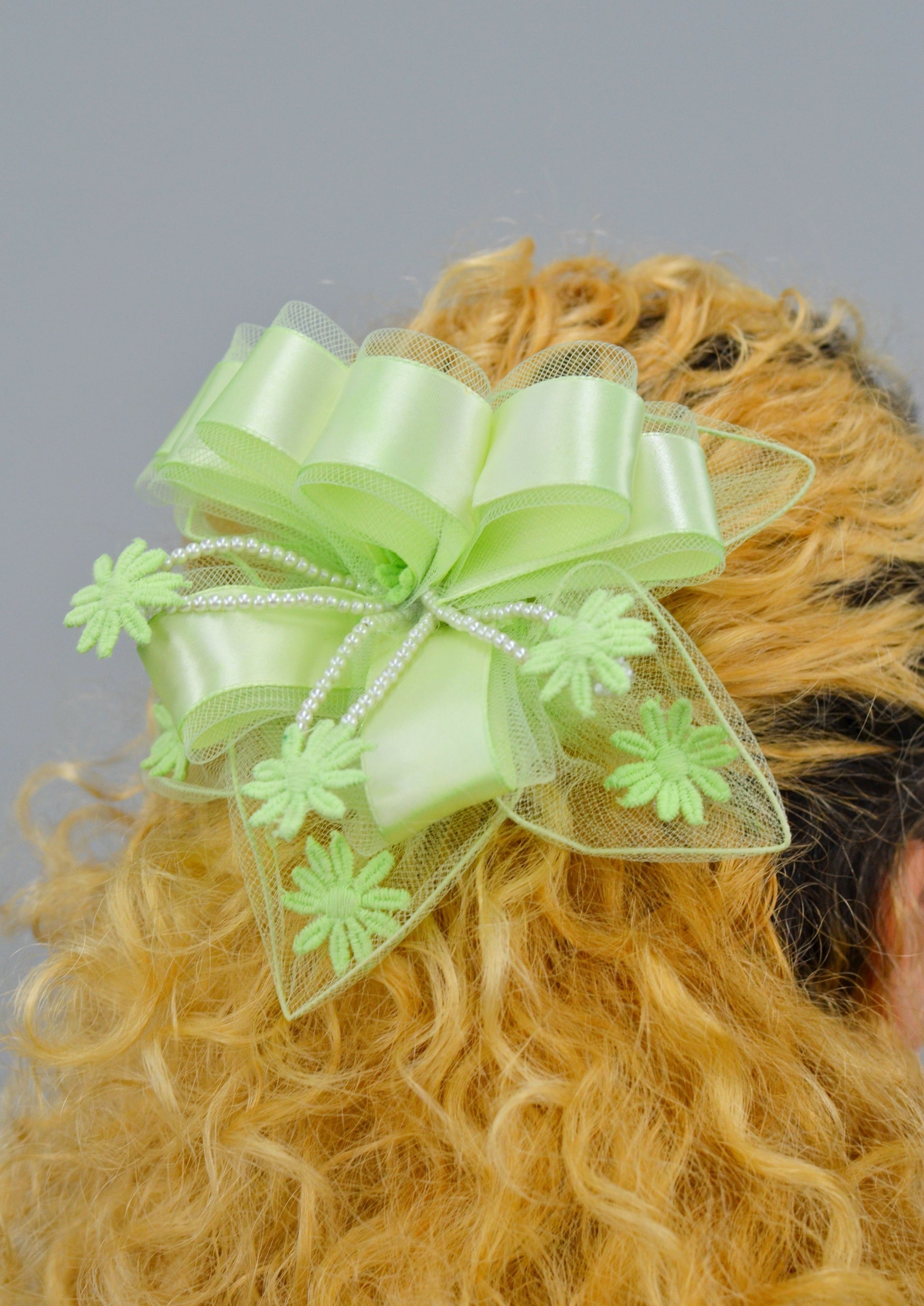 woman wearing a large lime green ribbon lace hair piece