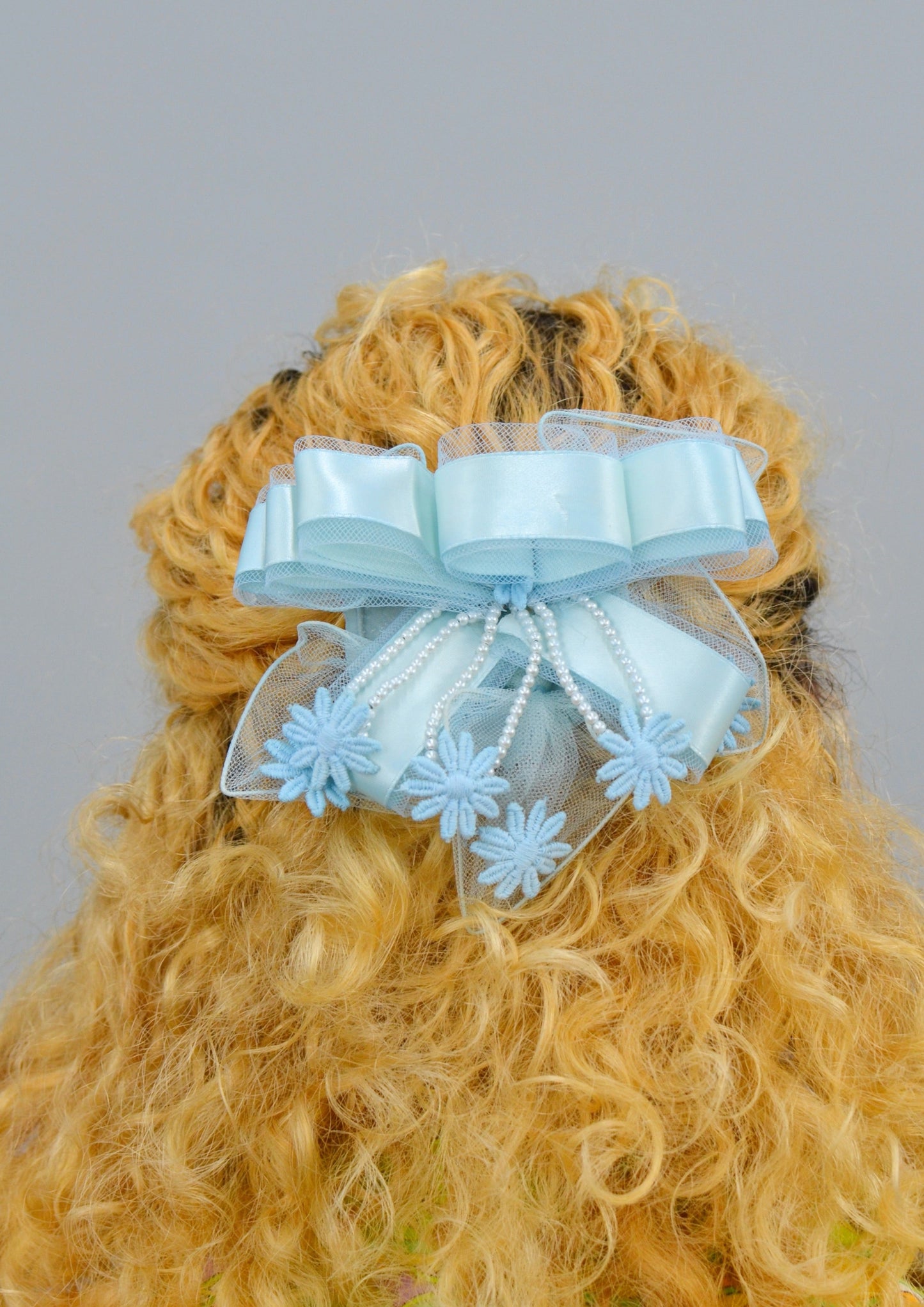woman wearing a large blue ribbon lace hair piece
