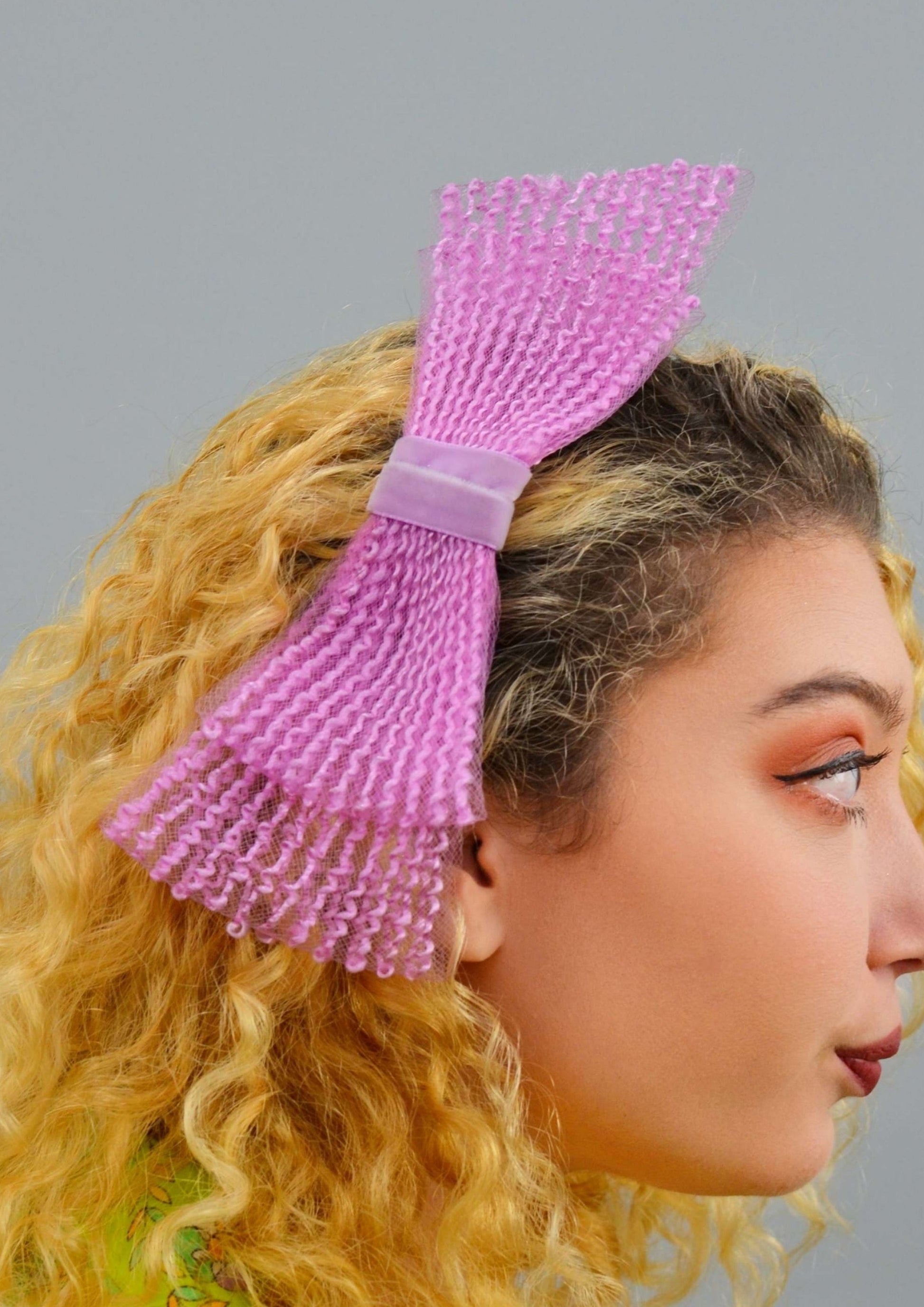 zoomed in photo of woman wearing a large bow shaped purple hair comb