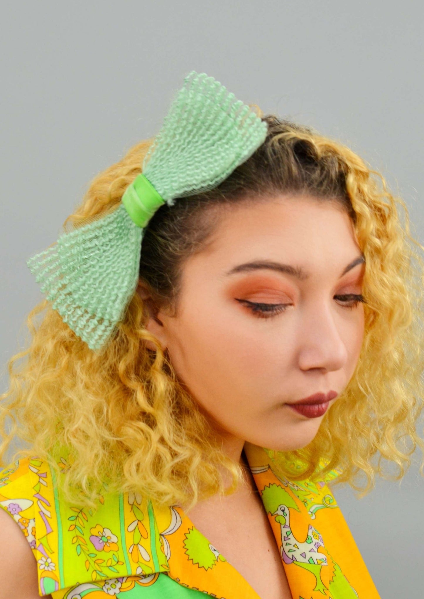 woman wearing a large bow shaped green hair comb