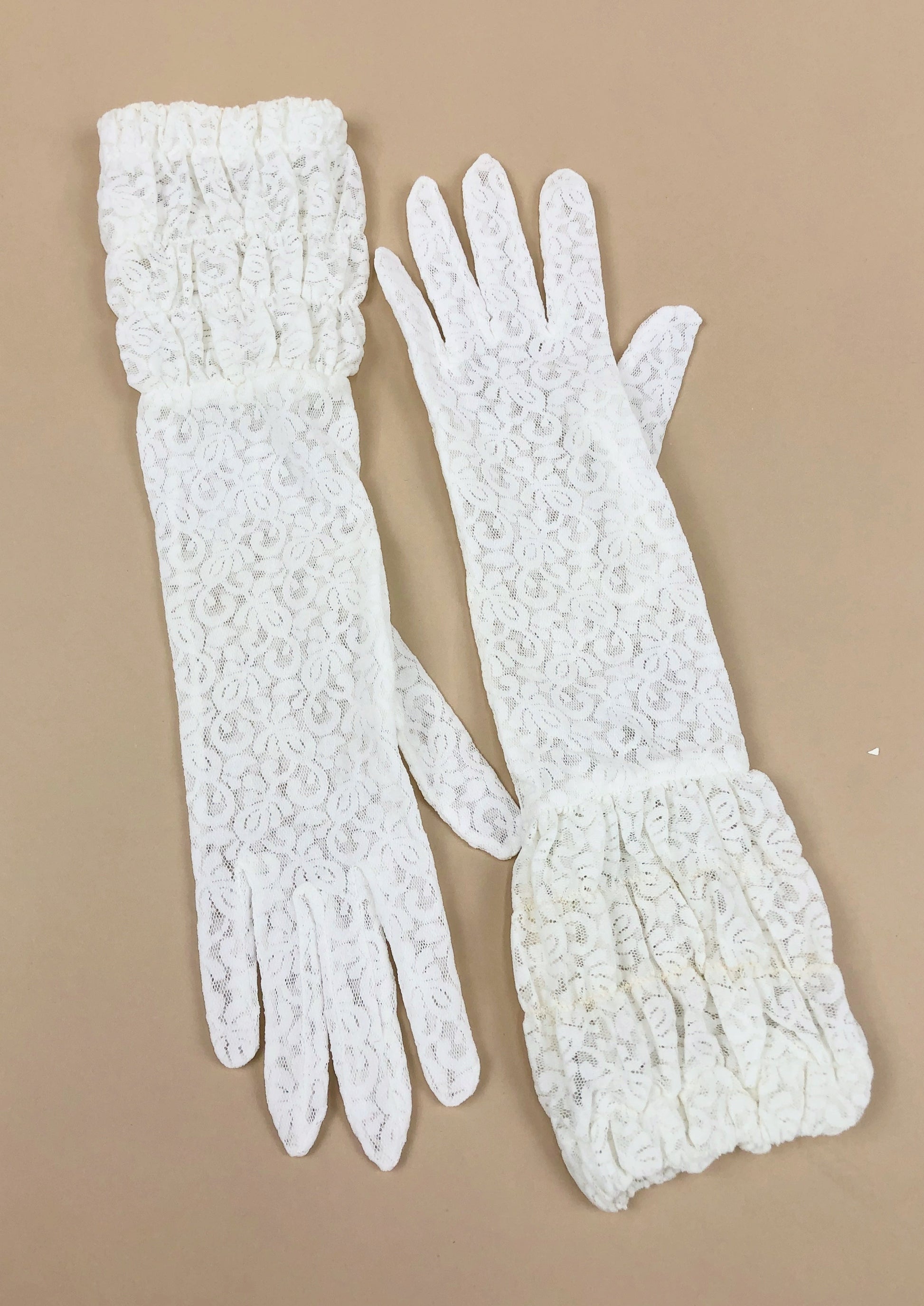 the Beatrice gloves, laying flat, are a paisley lace design with a large ruched cuff that ends at the mid arm