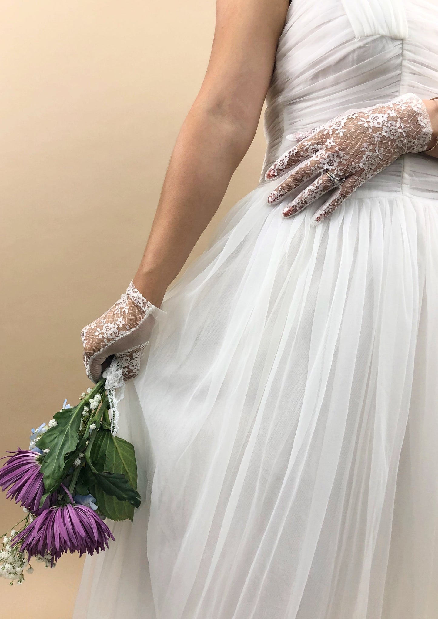 hands moving dress, hands have gloves on them and are also holding a bouquet