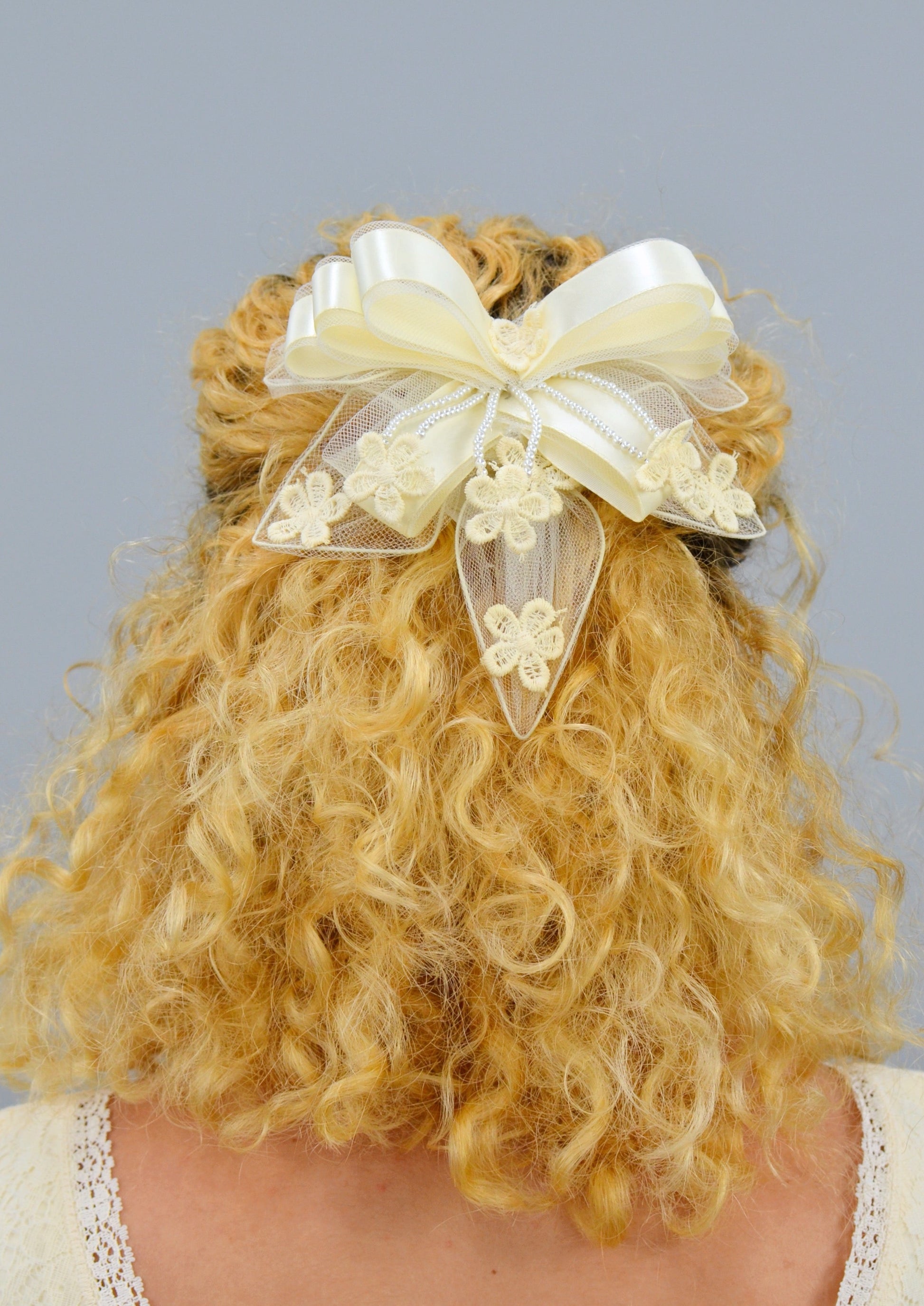 woman wearing a large ivory ribbon lace hair piece