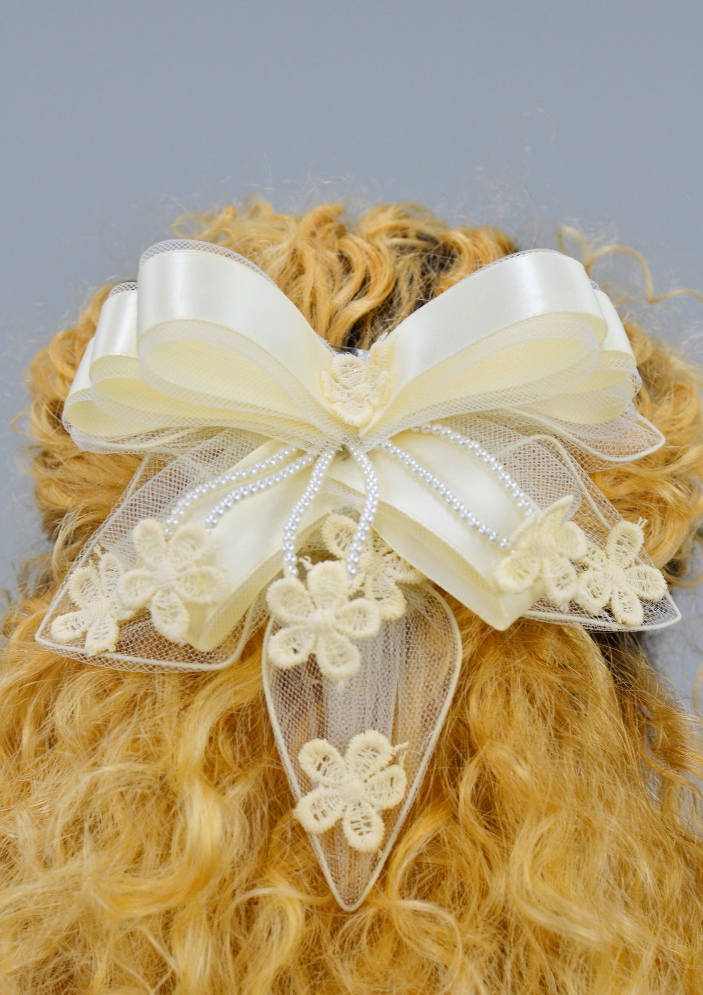 woman wearing a large ivory ribbon lace hair piece