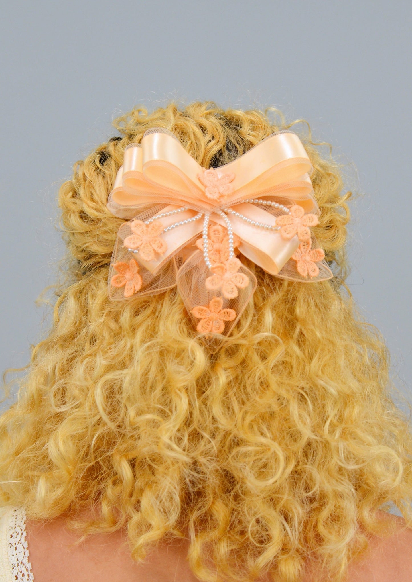 woman wearing a large peach ribbon lace hair piece